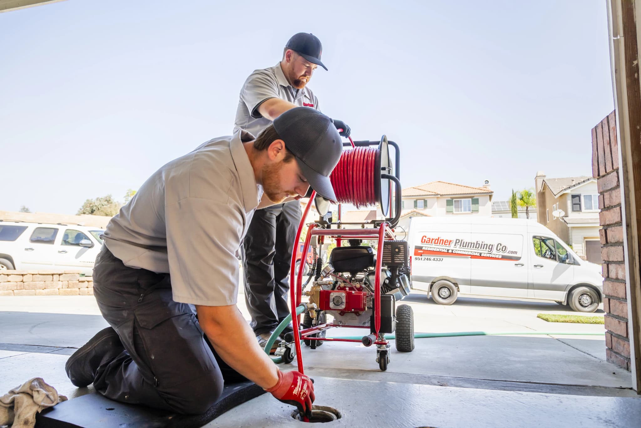 Professional plumbers using hydro-jetting equipment to clear drain